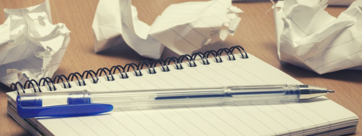 leerer Schreibblock und viel geknülltes Papier