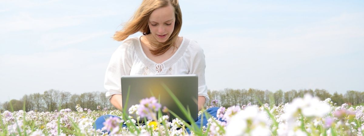 Frau mit Laptop auf Blumenwiese